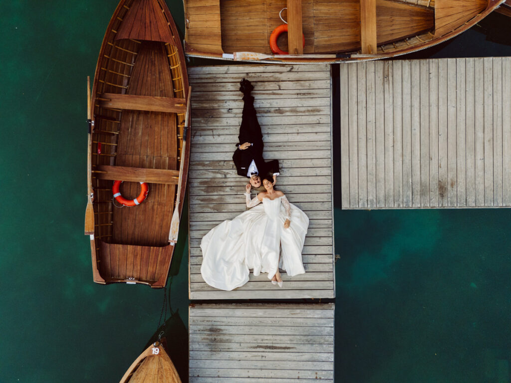 Aerial view of a couple during a Dolomites elopement surrounded by the blue water of Lago Di Braise.