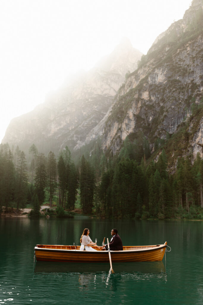 Couple rowing a wooden boat across Lago di Braies during their intimate Dolomites elopement in Italy.