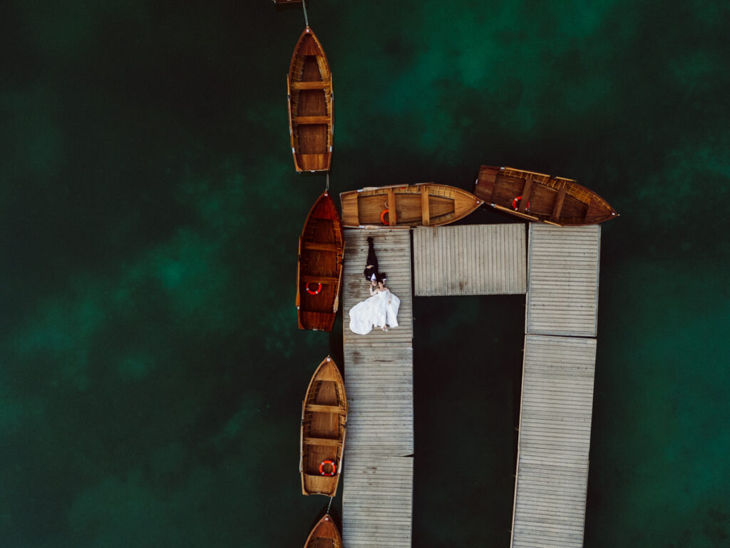 Aerial view of a couple during a Dolomites elopement surrounded by the dramatic peaks of the Italian Alps at Lago Di Braise.