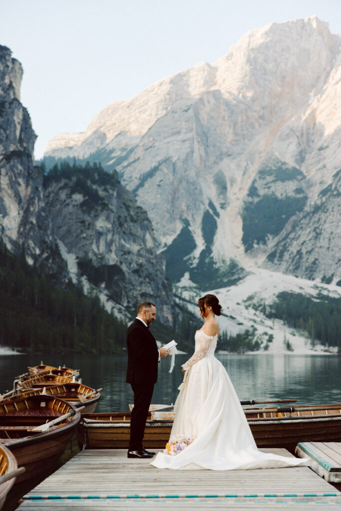 Couple exchanging private vows surrounded by the mountains during their intimate Dolomites wedding at Lago Di Braise.